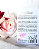 Pink rose beside packaged skincare product (rear label visible)